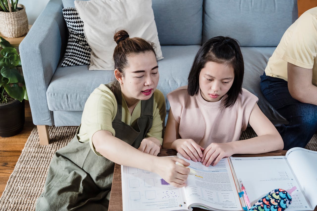 A mother helps her daughter with homework at a living room table for a learning experience.